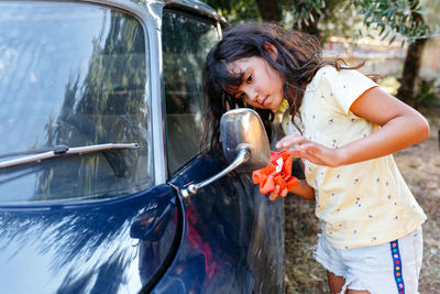 Girl watching a mirror of the car before washing it