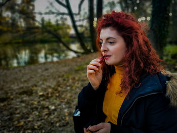 Portrait of beautiful woman holding camera at park