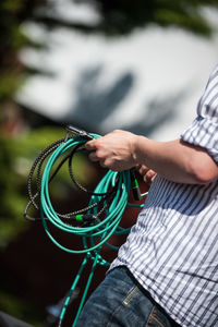 Midsection of man holding cables while standing outdoors