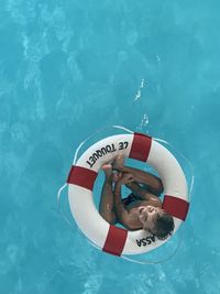 High angle view of boy in swimming pool with lifebuoy