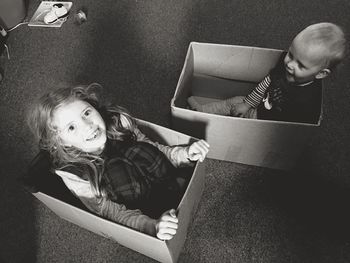 Cute siblings sitting in cardboard boxes at home