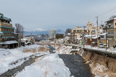 Snow covered buildings in city against sky