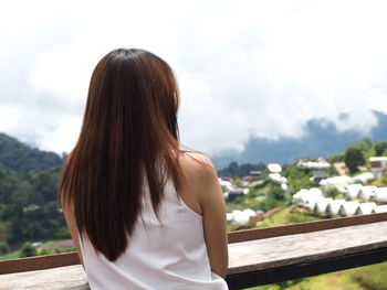 Rear view of woman standing by railing against sky