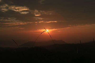 Silhouette landscape against orange sky