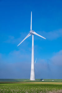 Low angle view of windmill on field against sky