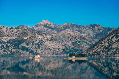 Scenic view of lake and mountains against clear blue sky