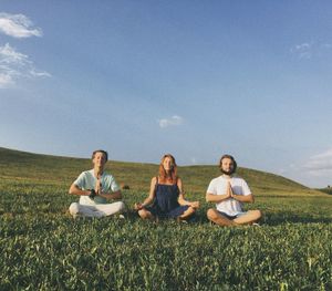 Friends practicing yoga on grassy field
