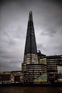 Low angle view of illuminated building against cloudy sky