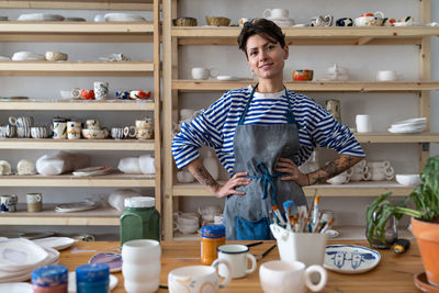 Successful self-employed female potter wearing apron at workplace in ceramic art studio