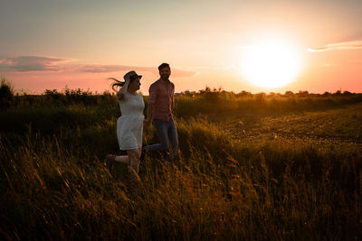 Couple on field against sky during sunset