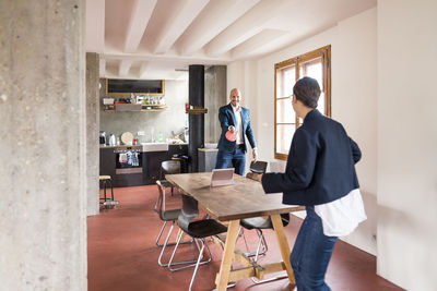 Carefree business people playing table tennis while standing at office