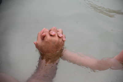 Low section of man and child holding hands at sea 