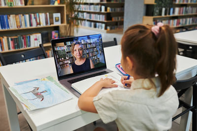 Rear view of woman using laptop on table