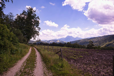 Empty road along landscape and mountains against sky