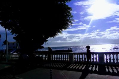 Silhouette people looking at sea against sky