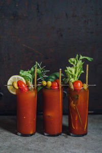 Bloody mary tomato brunch cocktail drink with celery, lemon, rosemary, pickles, olives, gold straw