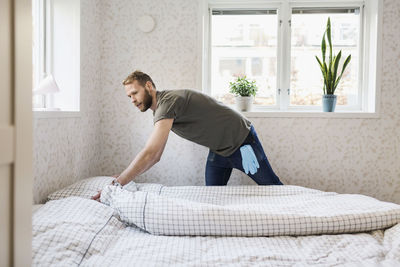 Side view of young man relaxing on bed at home