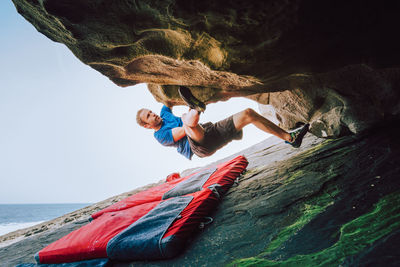 Man climbing on rock formation against sky