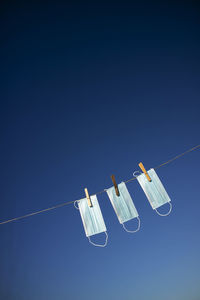 Low angle view of lighting equipment hanging against clear blue sky