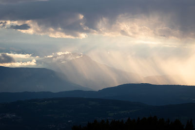 Sunlight streaming through clouds over landscape