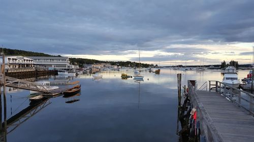 Boats moored at harbor in city against sky