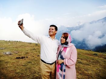 Happy man doing selfie with wife on field