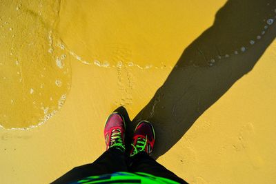 Low section of person standing on yellow water