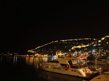 Illuminated harbor by buildings against clear sky at night