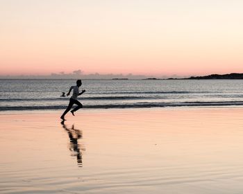 Silhouette people on beach against clear sky during sunset