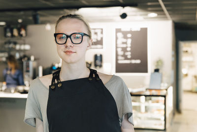 Portrait of confident transgender owner standing in coffee shop