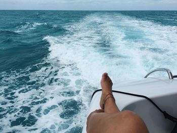 Low section of woman in boat on sea against sky