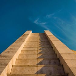 Low angle view of brown stairs leading to blue sky