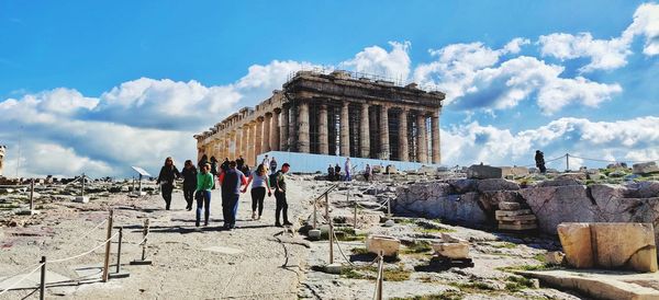 People at historical building against sky