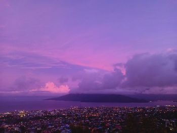 Illuminated city against sky at sunset