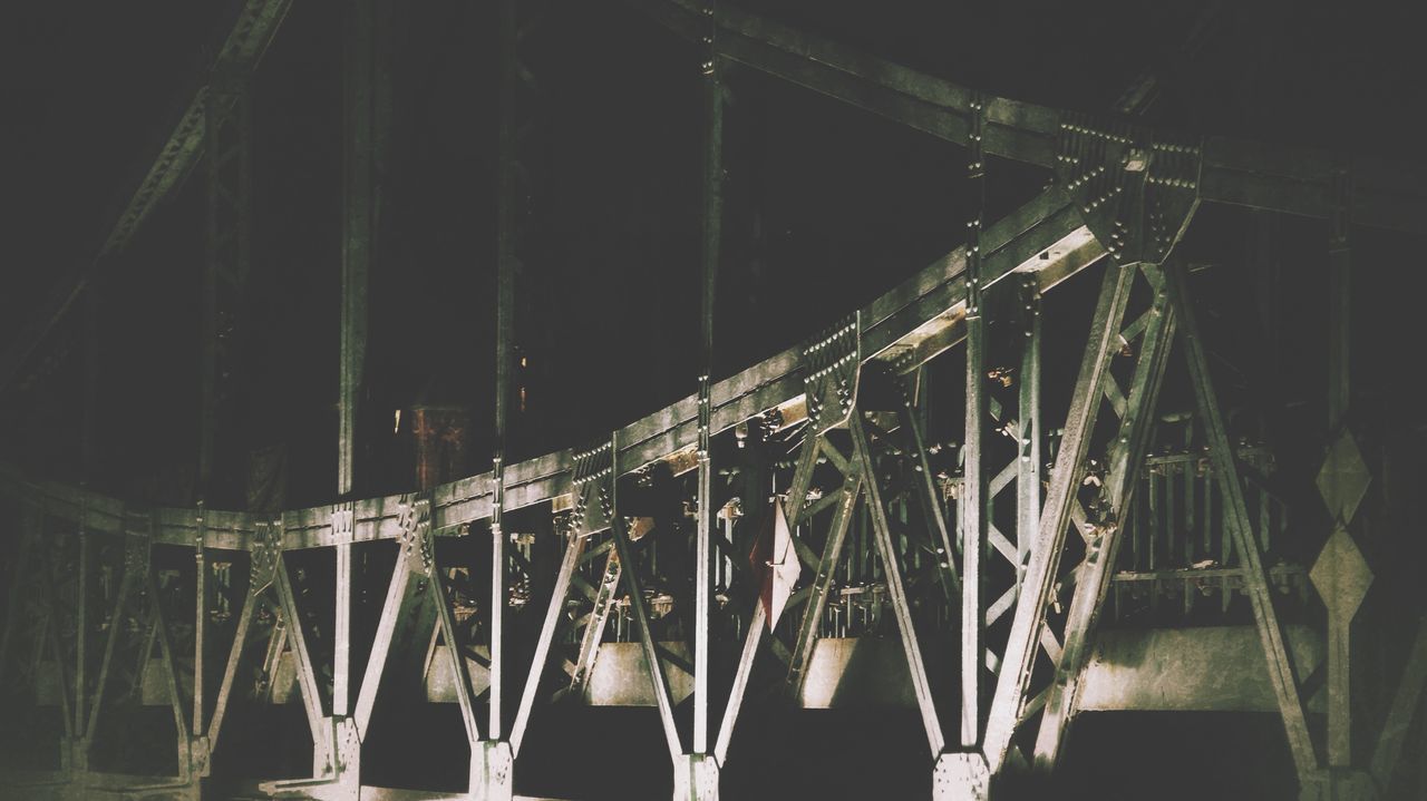 night, built structure, architecture, metal, in a row, illuminated, connection, bridge - man made structure, railing, low angle view, outdoors, no people, metallic, hanging, engineering, building exterior, side by side, fence, large group of objects, transportation