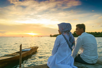 Man and woman looking at sea during sunset