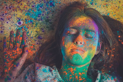 High angle view of young woman with face powder lying on floor