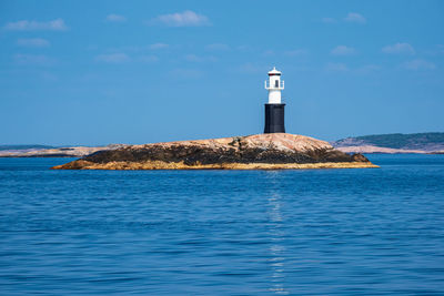 Lighthouse by sea against sky