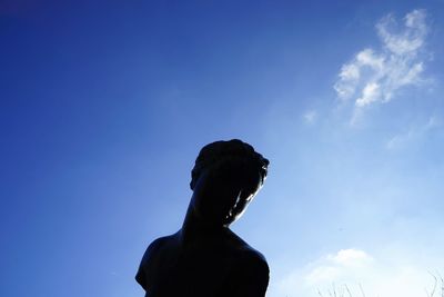 Low angle view of silhouette person against blue sky