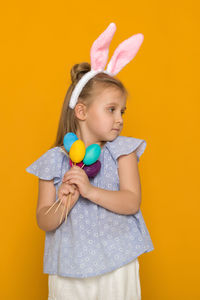 Midsection of woman holding easter egg against yellow background