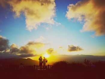 Silhouette people at observation point against sky during sunset