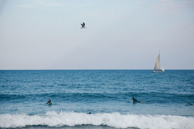 People surfboarding in sea against sky