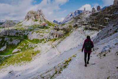 Rear view of woman walking on mountain against sky