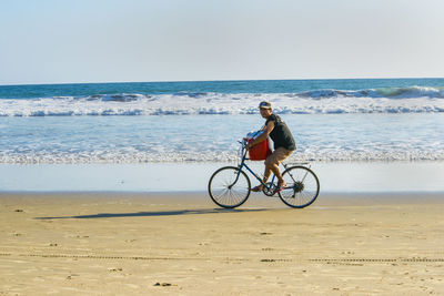Man riding bicycle on shore at beach