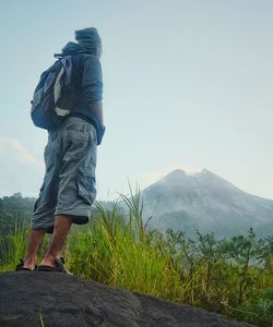 Rear view of man walking on mountain against sky