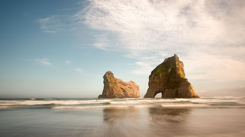 Rock formation on beach against sky