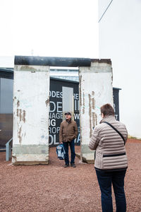 Rear view of friends standing against the wall