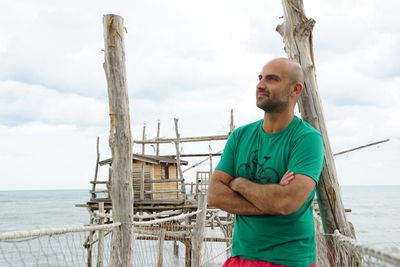 Bald man standing on pier over sea