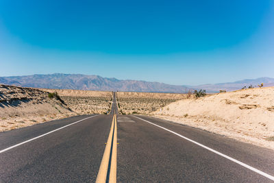 Empty road against clear blue sky