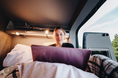 Low section of woman sitting on bed at home